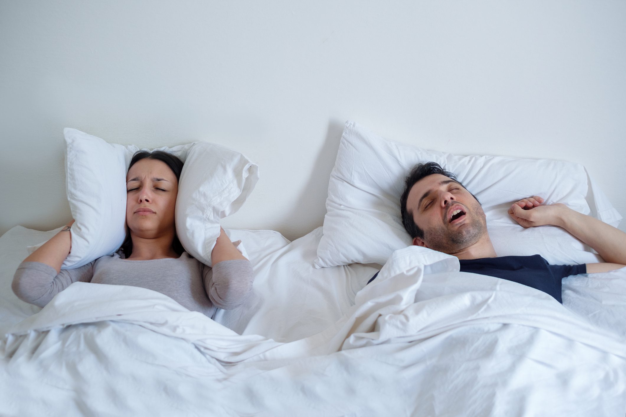 Woman suffering insomnia and man snoring in bed